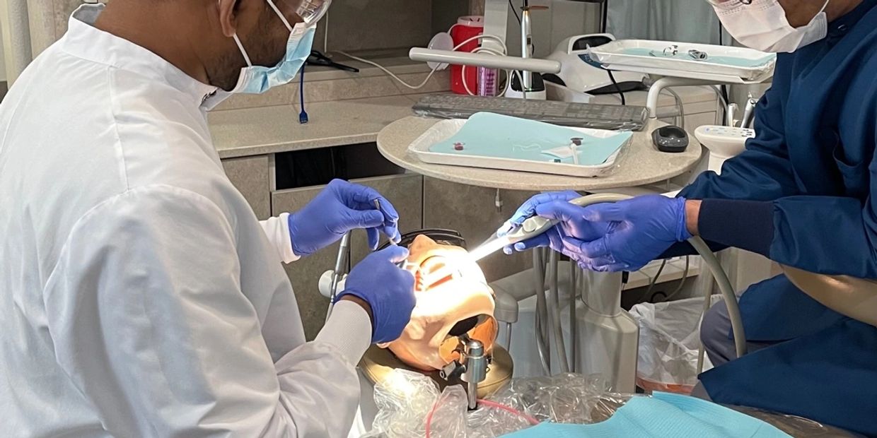 Two dentists perform a procedure on a dental mannequin in a clinic.
