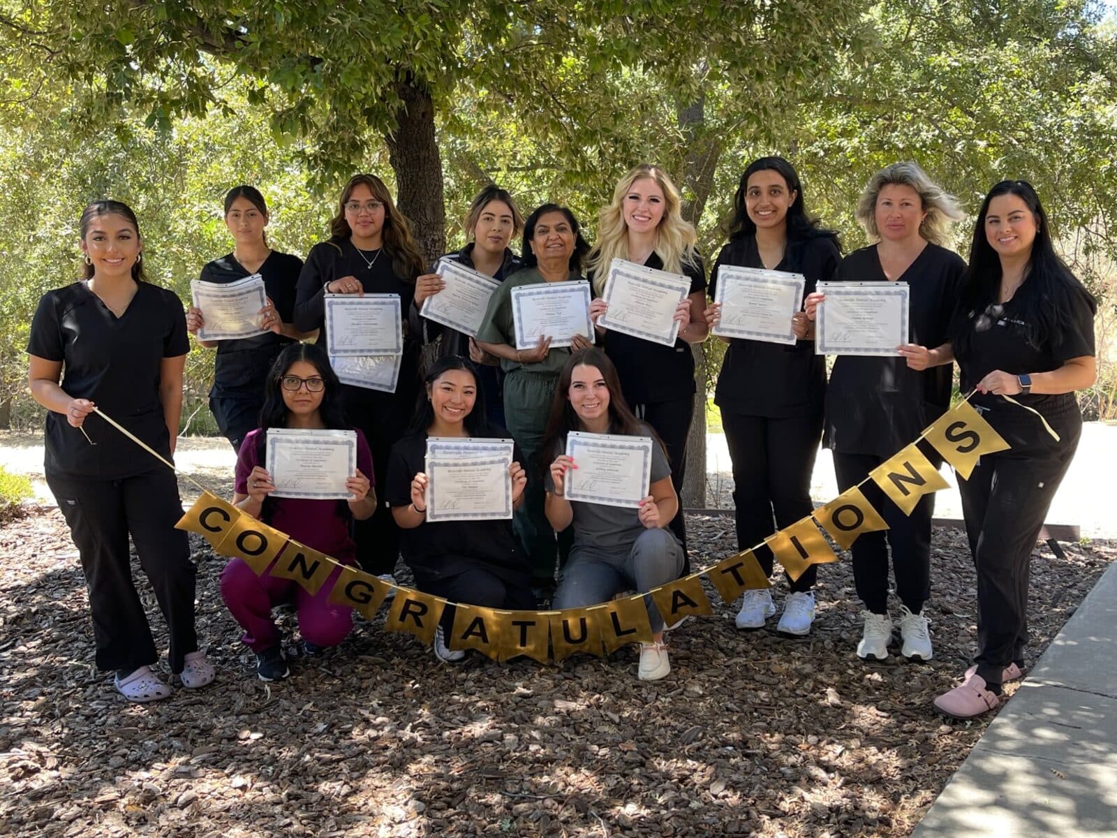 Roseville Dental Academy students holding completion certificates outside the academy.