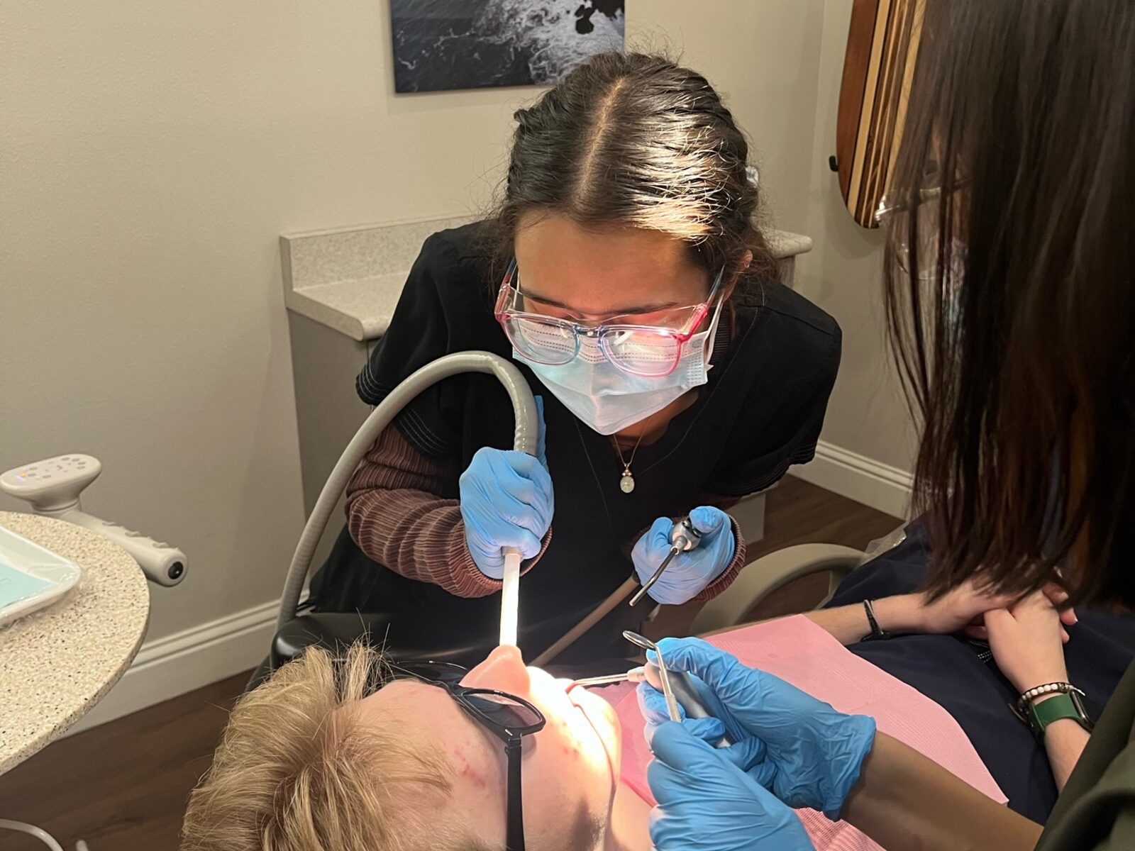 Instructor coaching a student through chairside dental assisting practice